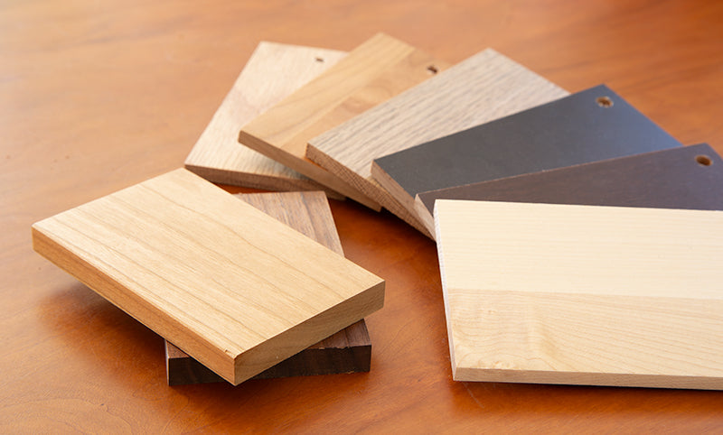 Various finishes of wood sample blocks arranged in a line.