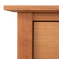 Close-up view of a Maple Corner Woodworks American Shaker 1-Drawer Enclosed Shelf Nightstand corner showing the edge and a drawer with a seamless design and a smooth, natural cherry wood grain finish.