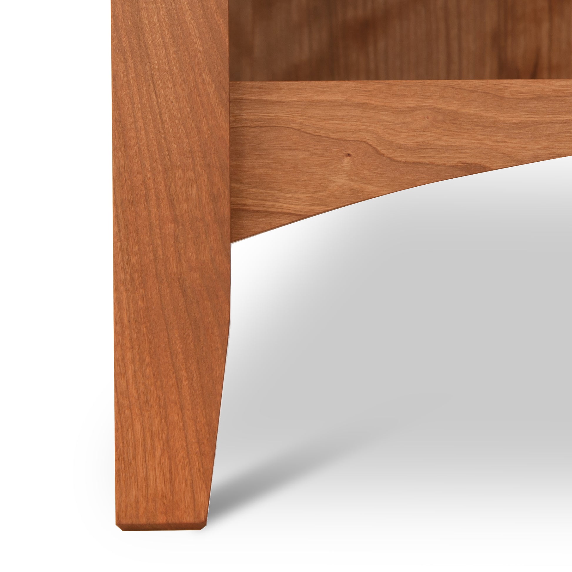 Close-up of a wooden table leg and corner with a natural finish, showcasing the rich hardwood grain and color, illustrating Vermont craftsmanship akin to Maple Corner Woodworks' American Shaker 1-Drawer Enclosed Shelf Nightstand.