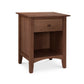 The Maple Corner Woodworks American Shaker 1-Drawer Enclosed Shelf Nightstand, exemplifying Vermont craftsmanship, with a smooth natural cherry finish featuring a single drawer and an open lower shelf, isolated on a white background. The nightstand has tapered legs and a