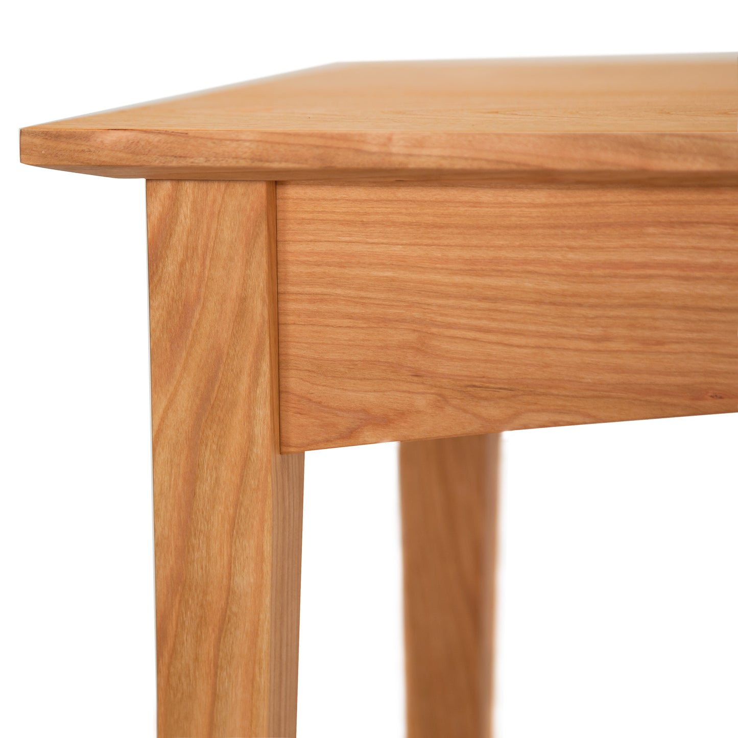 Close-up of an American Shaker Coffee Table corner from Maple Corner Woodworks showing the smooth surface and sturdy leg, with a clear wood grain pattern on a white background.