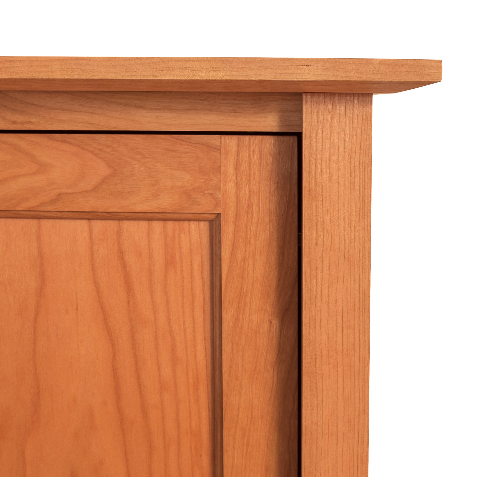 Close-up of an American Shaker Huntboard by Maple Corner Woodworks showing a detailed view of the door panel and frame with a smooth finish, emphasizing its craftsmanship and the natural cherry wood grain pattern.
