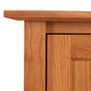 Close-up of an Maple Corner Woodworks American Shaker 67" TV Stand showing details of the grain and craftsmanship, including the joinery of the top panel and a partial view of a cabinet door.