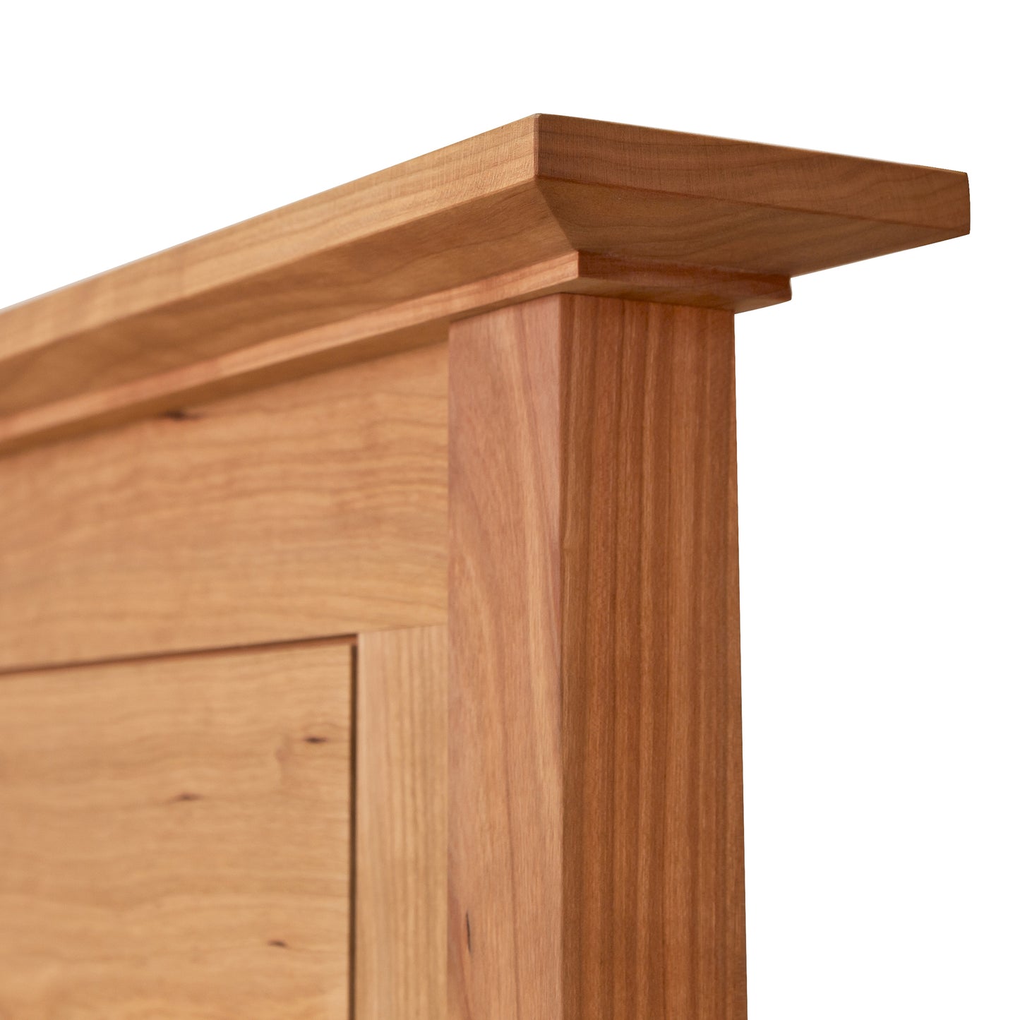 Close-up of the corner of a wooden cabinet showing detailed wood grain and craftsmanship. The design features a smooth, polished finish and joins between the American Shaker Panel Bed and vertical side by Maple Corner Woodworks.