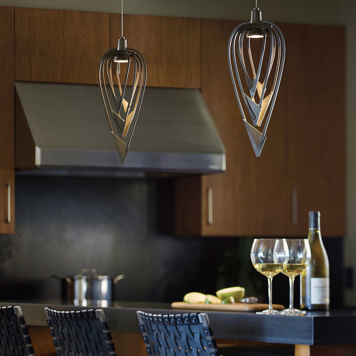 A kitchen with a wine glass hanging from a Hubbardton Forge Amulet Mini Pendant lighting fixture.