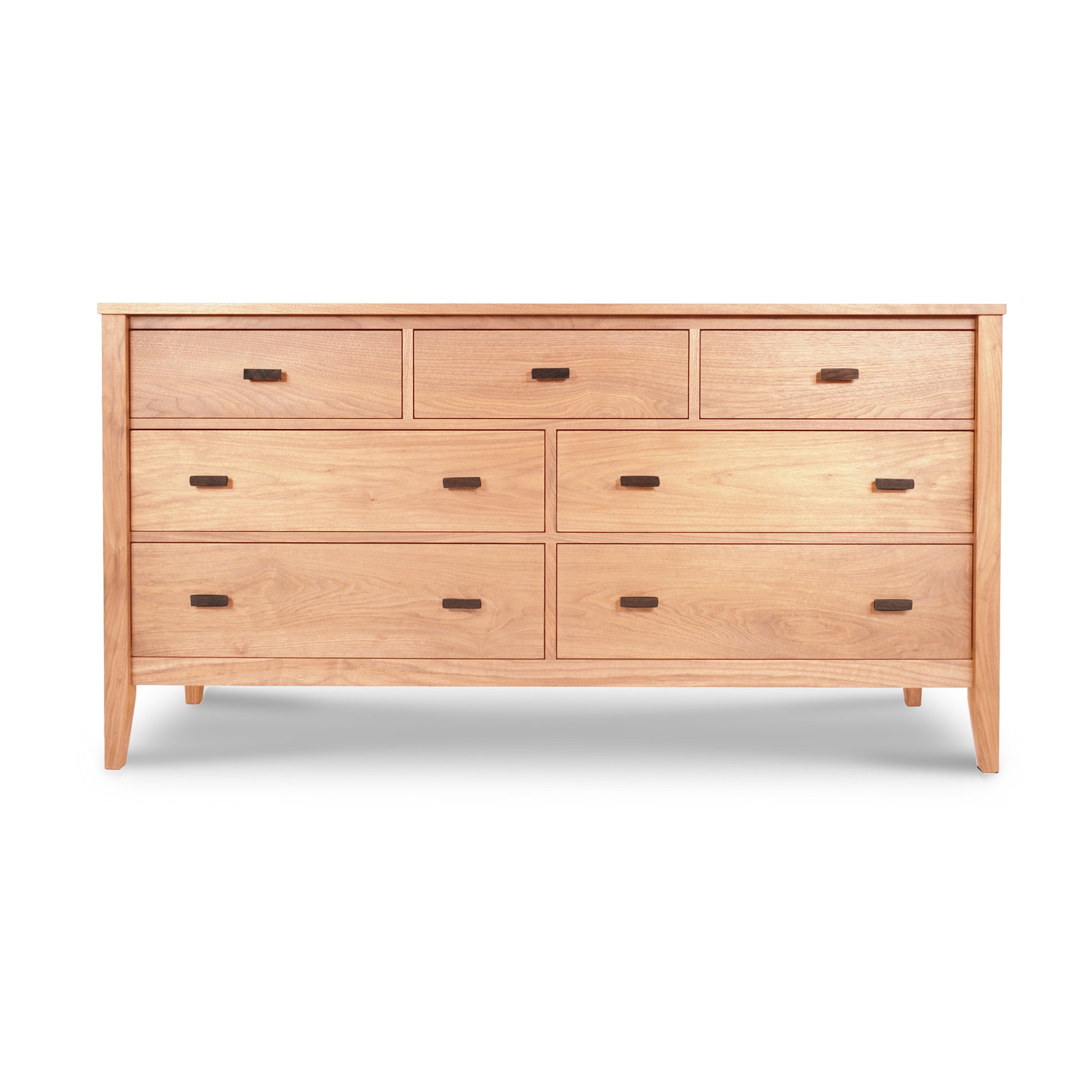 An eco-friendly Andover Modern 7-Drawer Dresser with seven drawers and round handles, featuring a natural cherry finish and angled legs, isolated on a white background. (Maple Corner Woodworks)