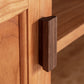 Close-up view of a dark brown, rectangular wooden drawer handle on an Andover Modern 64" TV Stand by Maple Corner Woodworks. The focus is on the texture and Vermont craftsmanship of the wood.