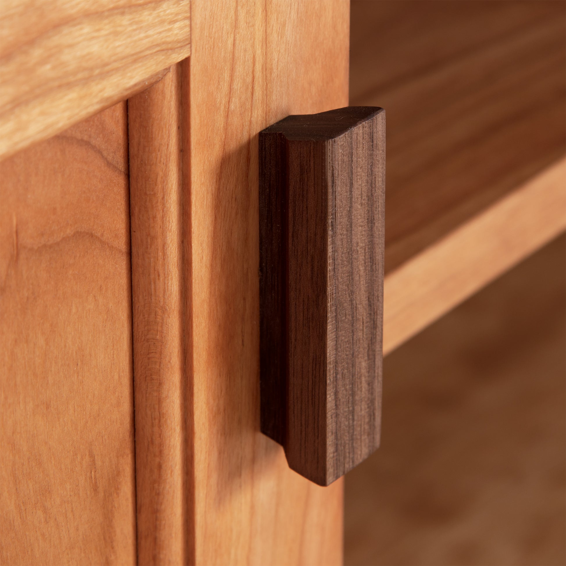 Close-up view of a dark brown, rectangular wooden drawer handle on an Andover Modern 64" TV Stand by Maple Corner Woodworks. The focus is on the texture and Vermont craftsmanship of the wood.