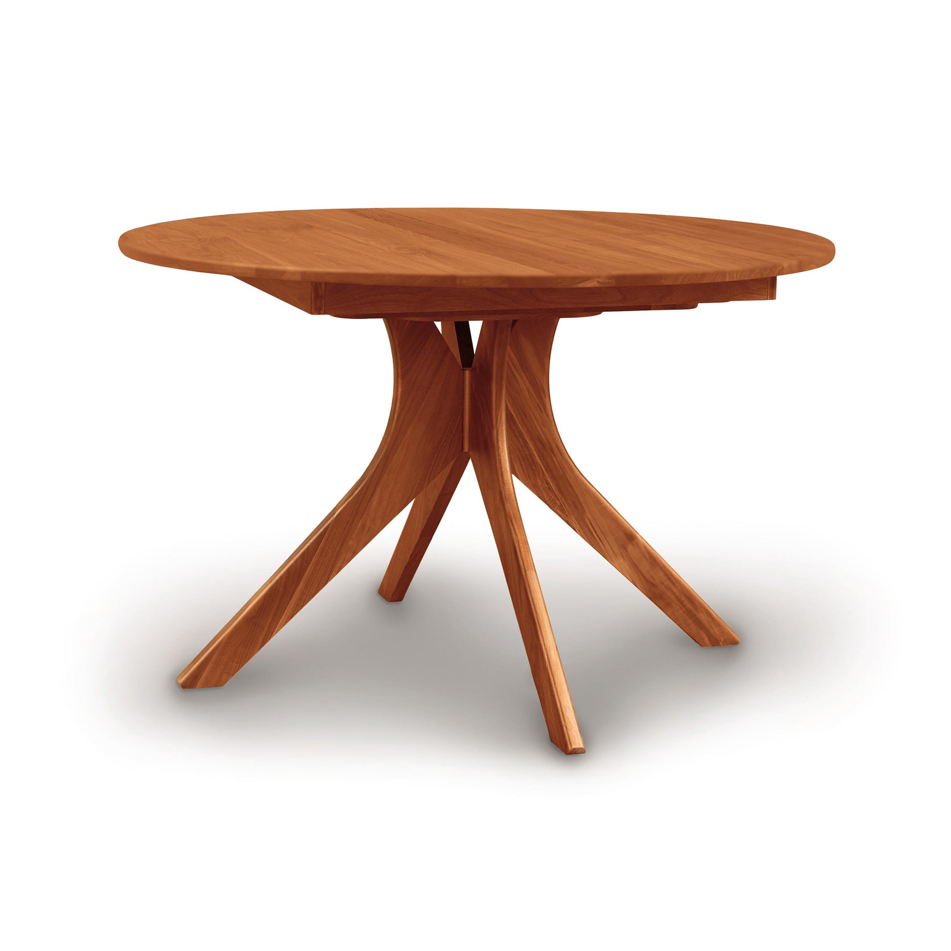 Copeland Audrey Round Extension Dining Table crafted from solid wood, showcasing a sleek round top and distinctive angled legs.