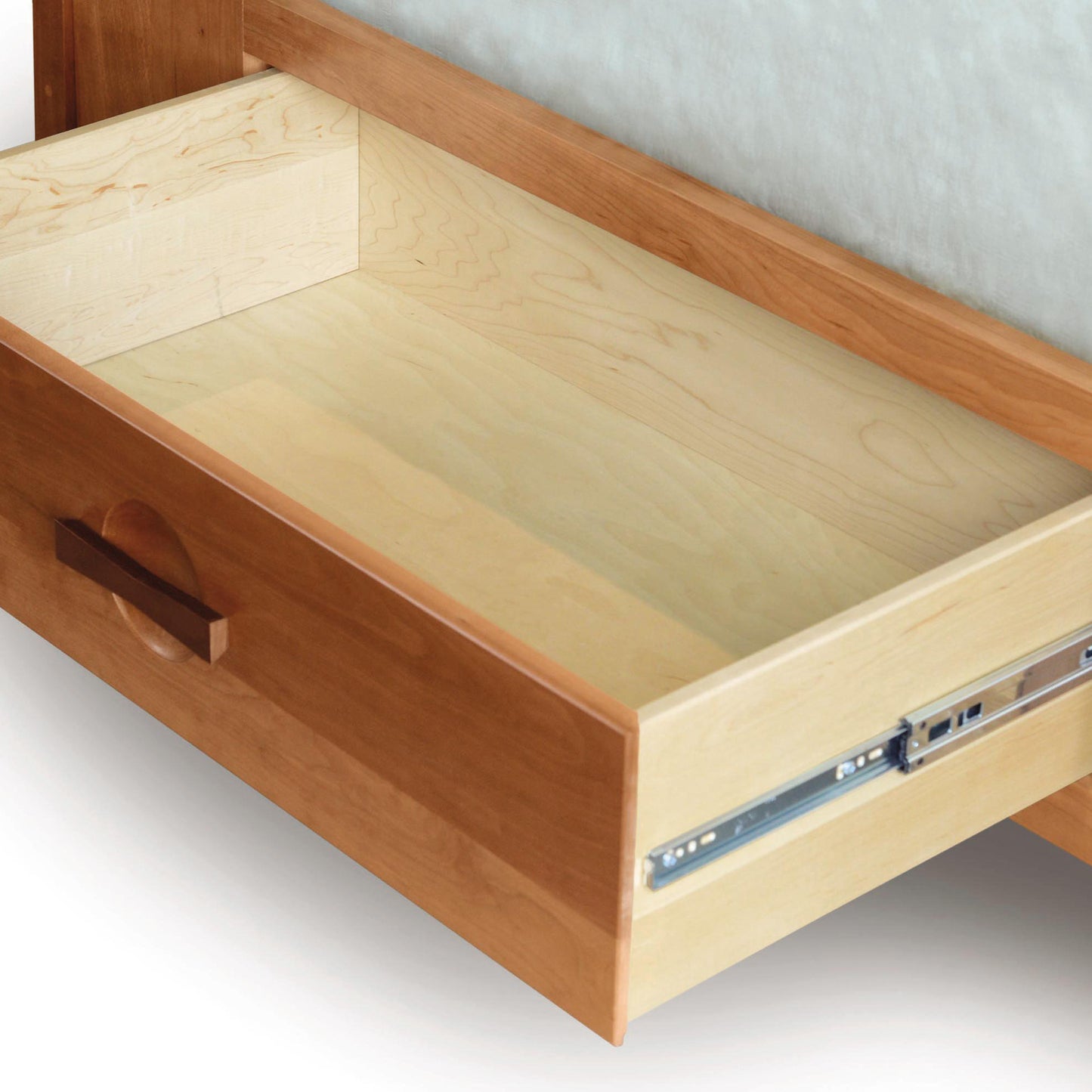 An open wooden drawer, designed in the American Craftsman style, showcasing its empty interior and metal sliding mechanism from the Copeland Furniture Berkeley Cherry Storage Bed.