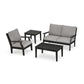 A modern POLYWOOD Braxton 4-Piece Deep Seating Set featuring a black frame includes a sofa, two armchairs with gray cushions, and a rectangular coffee table. The furniture, made from POLYWOOD