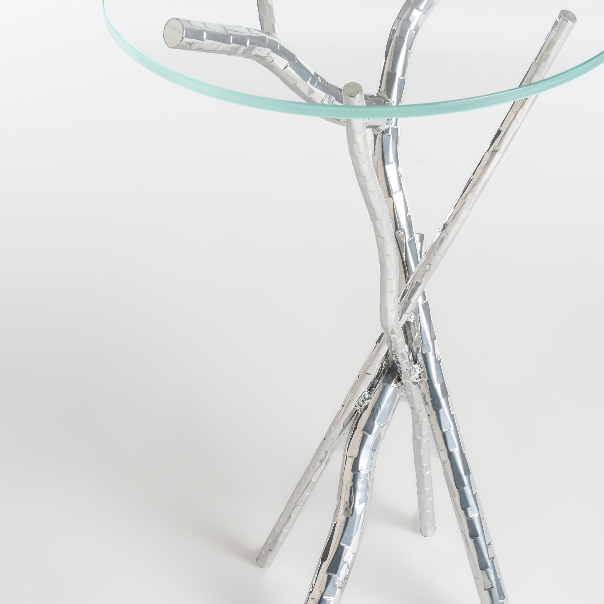 Brindille Accent Table by Hubbardton Forge with tempered glass top and artistic tripod base of intertwined metallic branches.