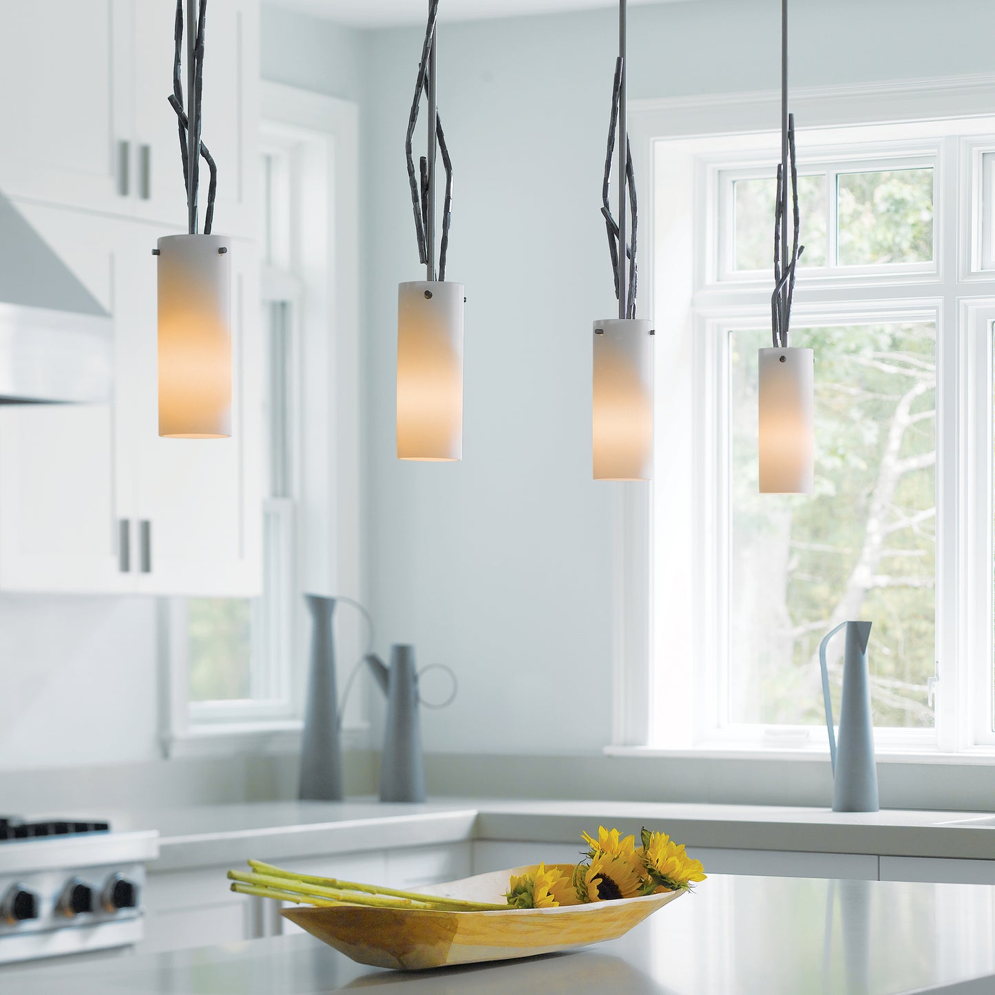 Hubbardton Forge Brindille Mini Pendant illuminating a modern kitchen with white cabinets.