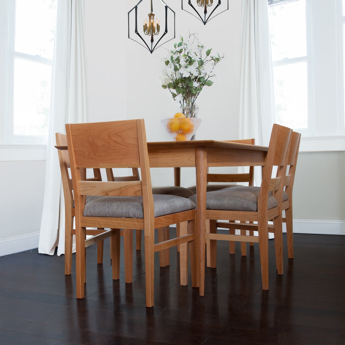 A dining room with a Burke Modern Dining Table and chairs, showcasing exquisite craftsmanship by Vermont Woods Studios.