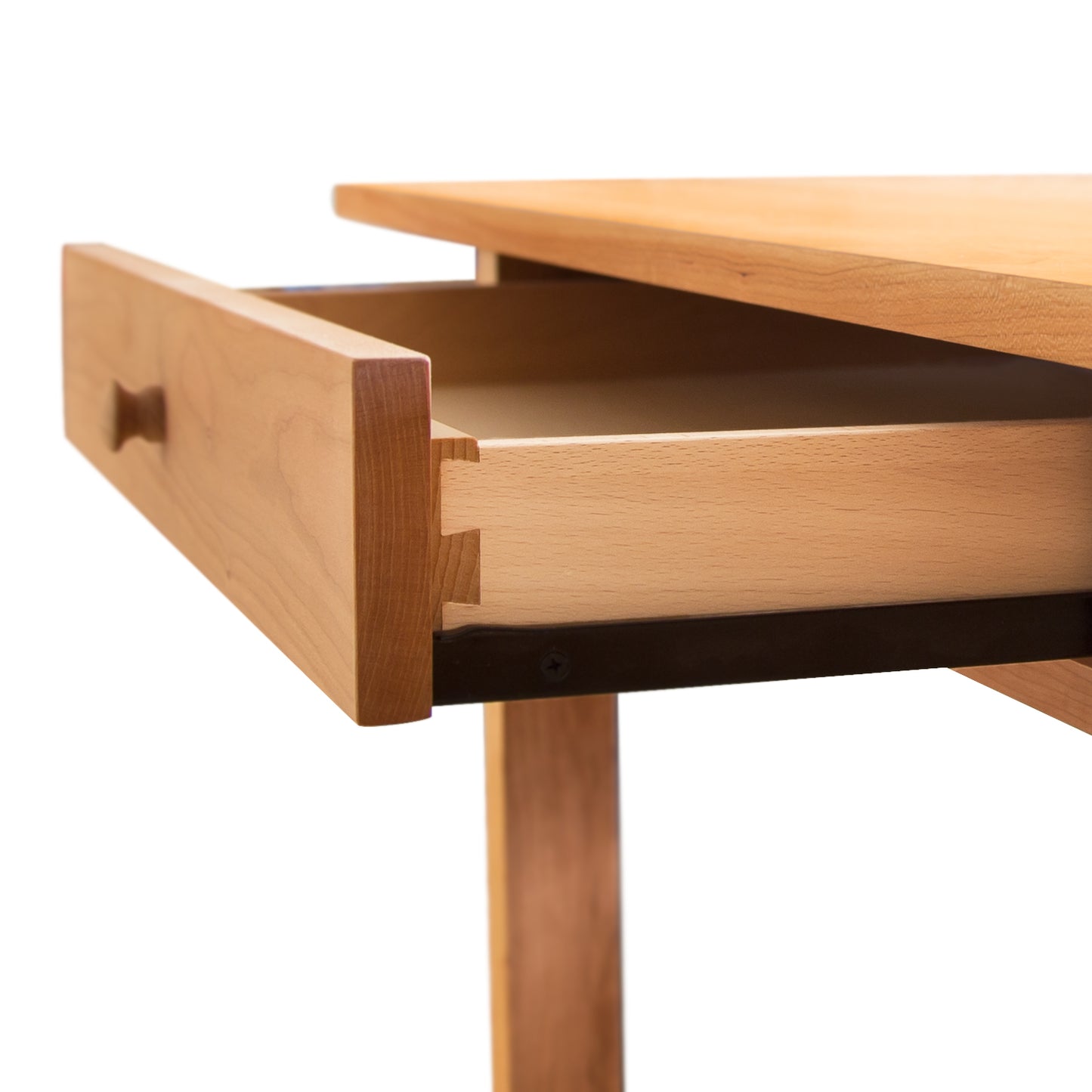 An open wooden drawer in a Vermont Furniture Designs Burlington Shaker Study Desk, showcasing its dovetail joint construction, against a white background.