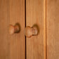 Solid wood Burlington Shaker Tall Storage Chest doors with round knobs, one knob in sharp focus and the other slightly out of focus.