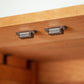 Two metal drawer handles attached to a contemporary Vermont Furniture Designs Burlington Shaker Tall Storage Chest, viewed from below.