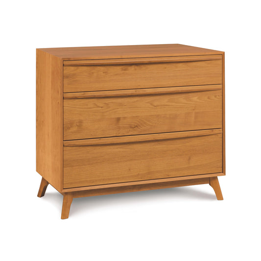 A solid natural cherry Copeland Furniture Catalina 3-Drawer Chest with angled legs isolated on a white background.