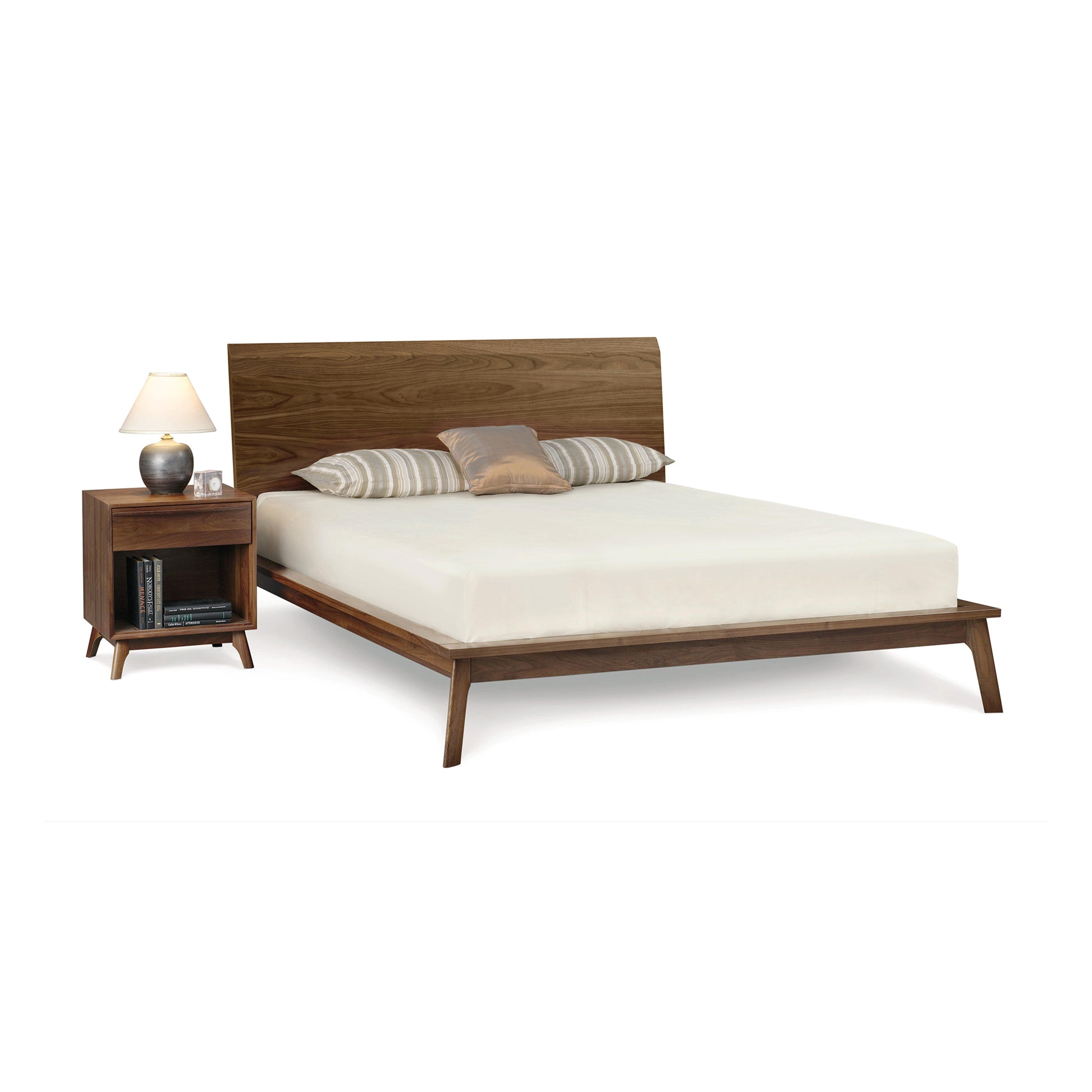 A modern American black walnut wood Copeland Furniture Catalina platform bed with matching nightstand and a lamp, set against a white background.