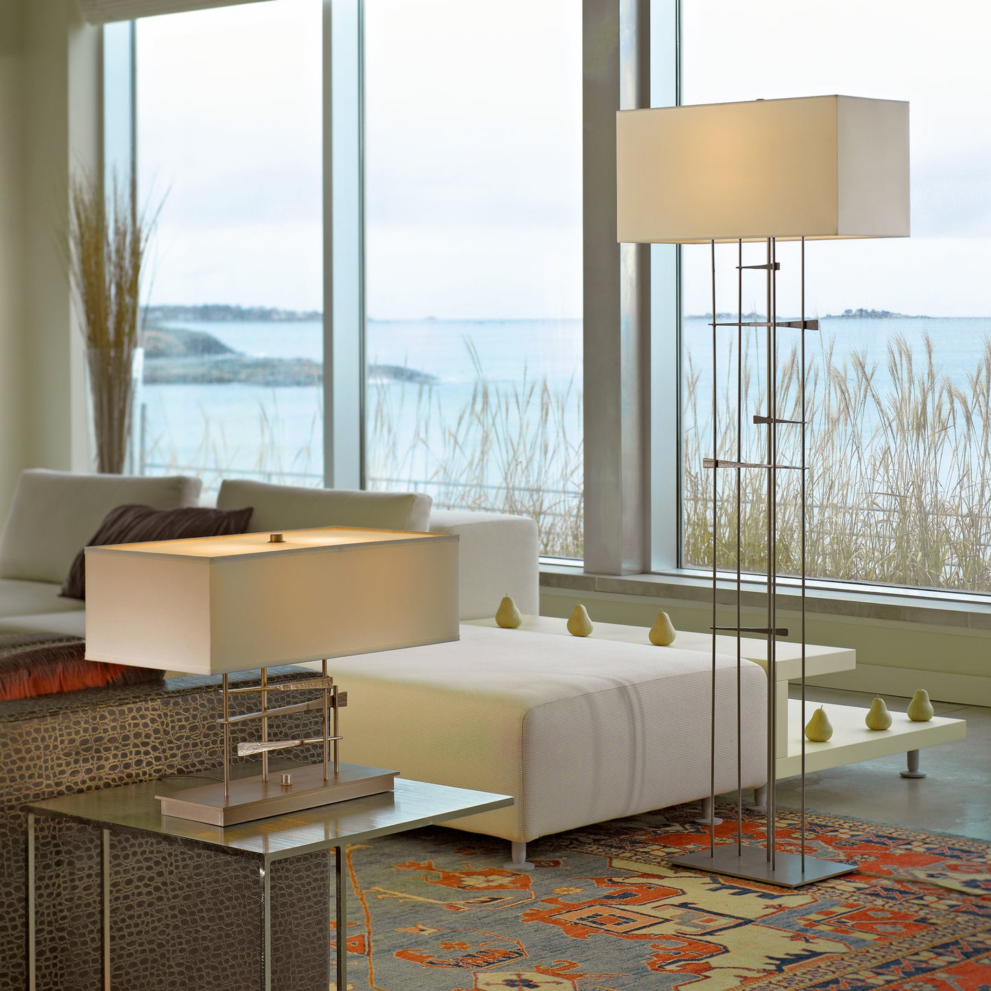 White sofa and geometric rug with Hubbardton Forge Cavaletti Table Lamps featuring forged iron frames.