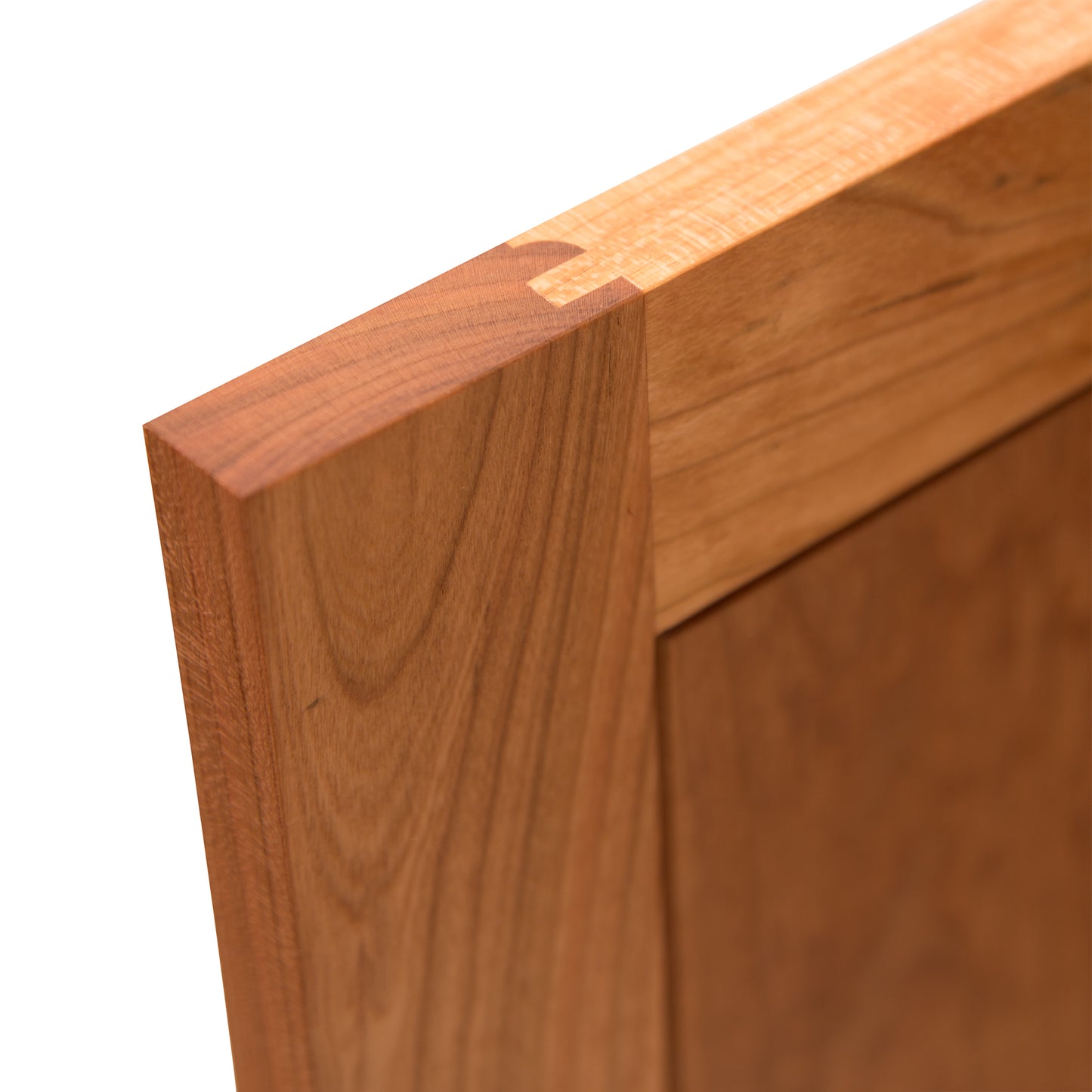 Close-up of a dovetail joint connecting two solid hardwood pieces, highlighting the smooth grain and precision of the craftsmanship against a white background on the Cherry Moon Small 38" Sideboard by Maple Corner Woodworks.