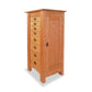 A Maple Corner Woodworks Cherry Moon Jewelry Cabinet with multiple drawers on one side and a single door on the other, isolated on a white background.