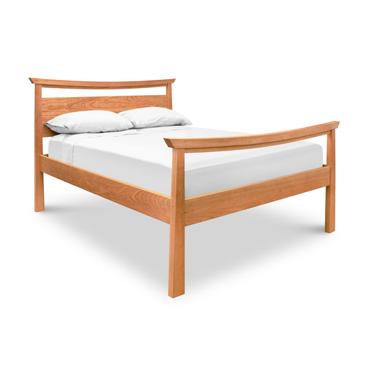 A simple Maple Corner Woodworks Cherry Moon Pagoda Bed frame with a headboard, fitted with a white mattress and two white pillows, isolated on a white background.