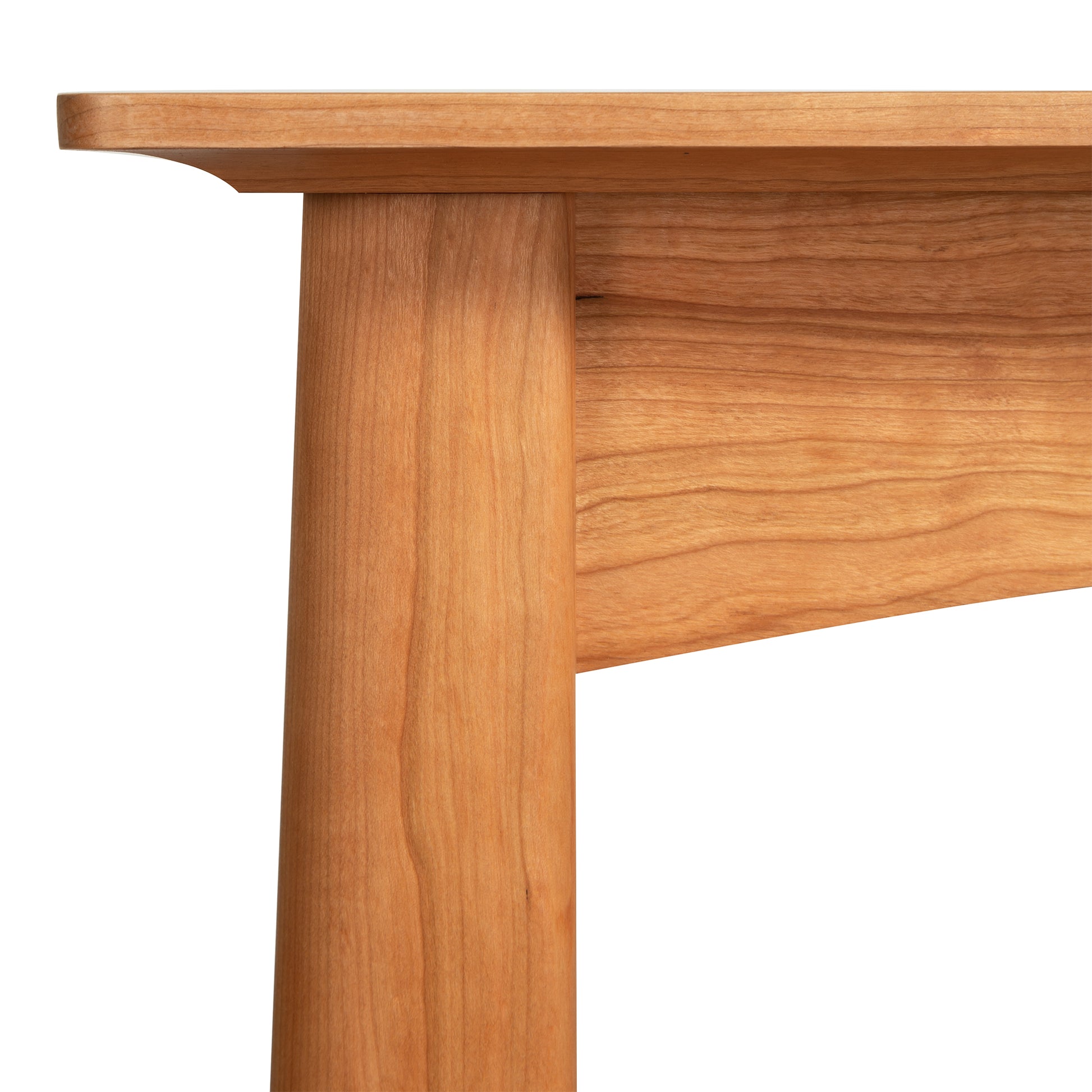 Close-up view of a Maple Corner Woodworks Cherry Moon Sofa Table, highlighting the smooth surface of the tabletop and the grainy texture of the table leg and support beam.