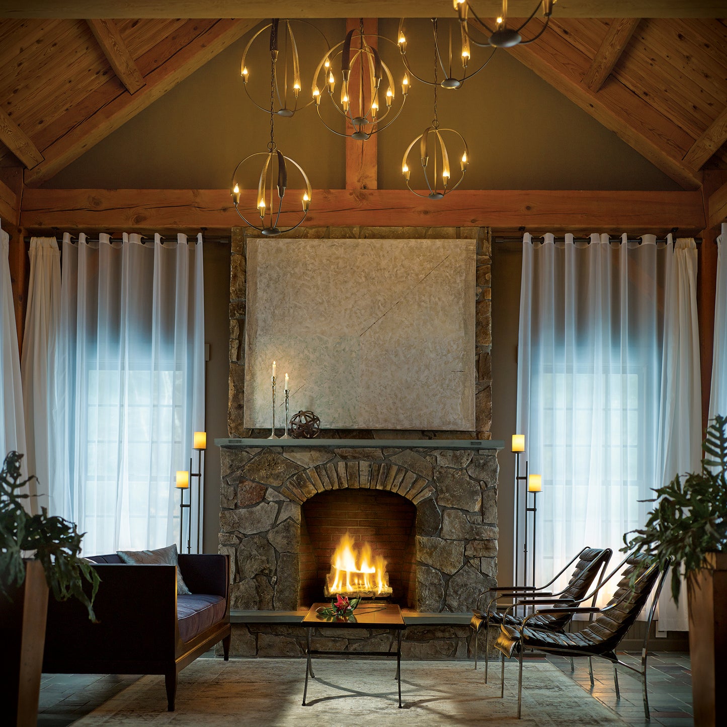 A living room in Vermont with a fireplace illuminated by a Hubbardton Forge Cirque Chandelier.