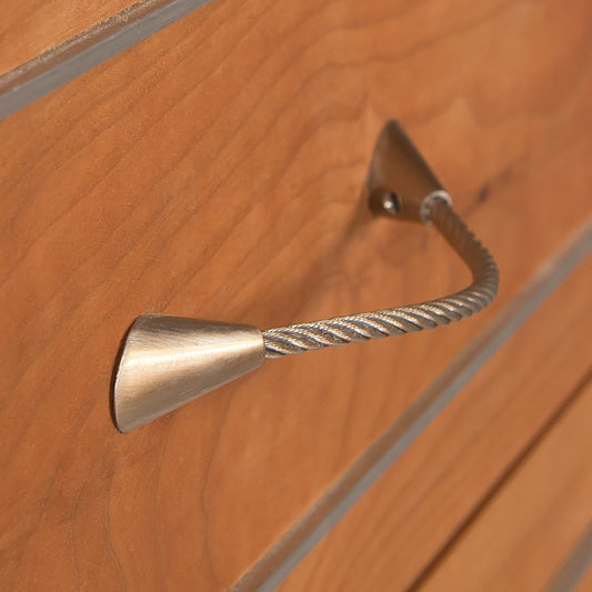 Detail view of the Contemporary Cable 9-Drawer Dresser by Vermont Furniture Designs, highlighting its unique twisted metal drawer pull.