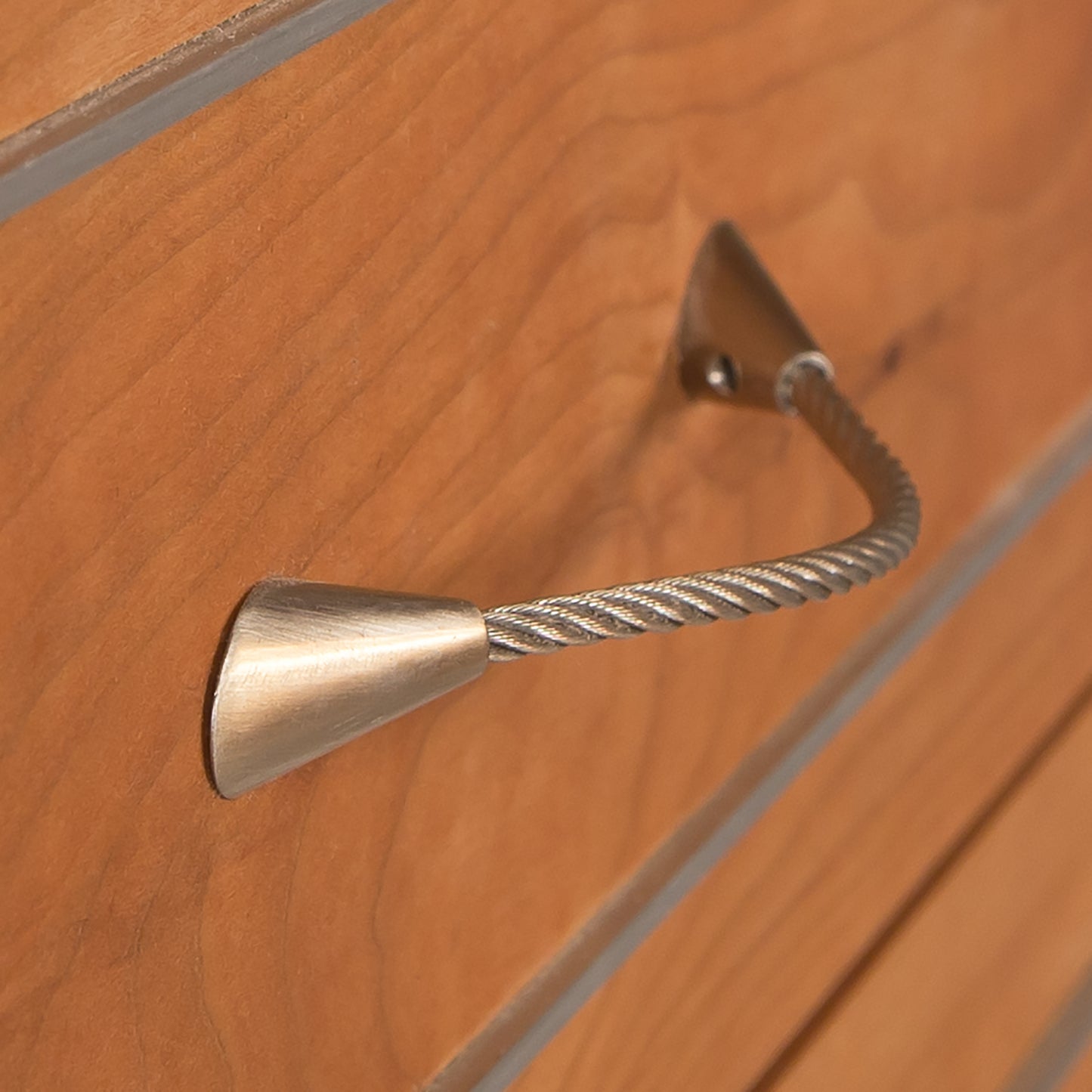 Metal doorstop with a rubber tip mounted on a Vermont Furniture Designs Contemporary Cable 5-Drawer Chest.