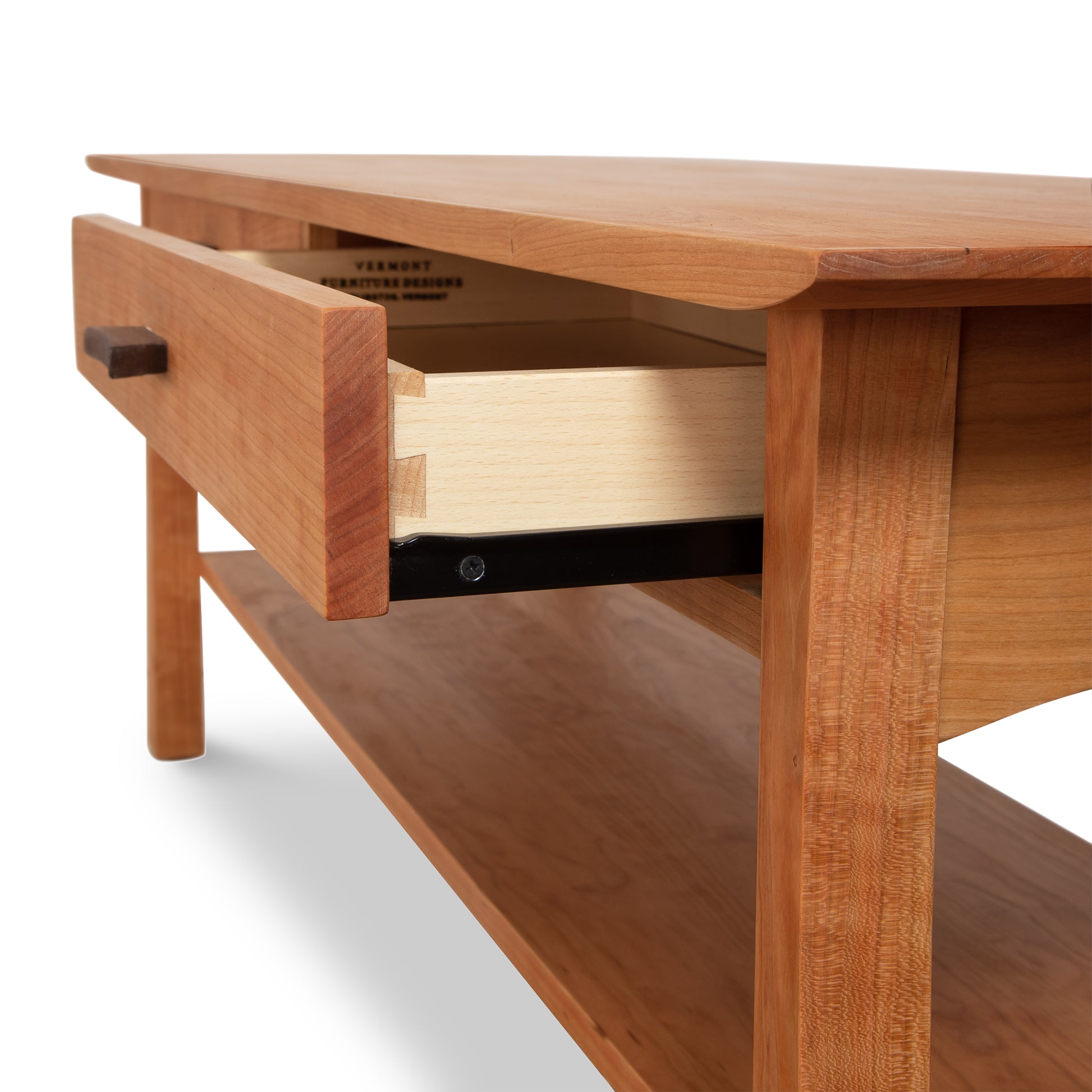 A close-up view of a solid hardwoods Vermont Furniture Designs Contemporary Craftsman Console Coffee Table with an open drawer, revealing its construction and the dovetail joints that connect the drawer to its face.