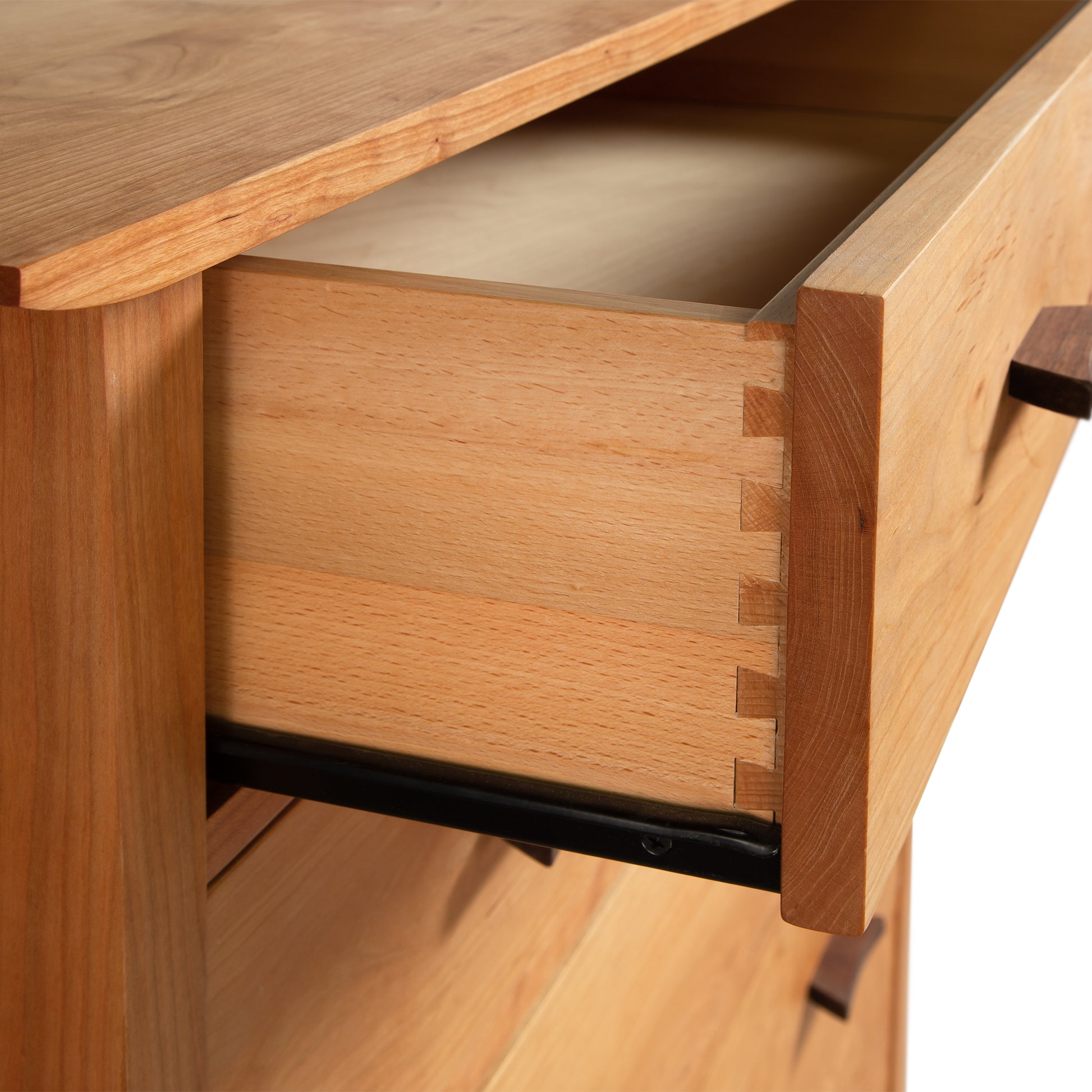 Open wooden drawer showing dovetail joints and a metal slide mechanism in a Vermont Furniture Designs Contemporary Craftsman 5-Drawer Chest.