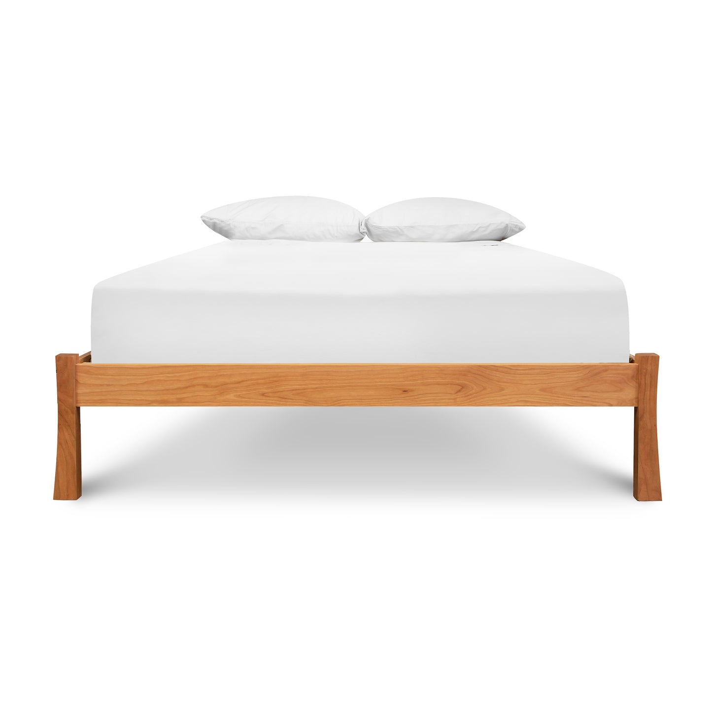 A Vermont Furniture Designs Contemporary Craftsman Studio-Style Platform Bed frame made from sustainably sourced hardwood, supporting a mattress covered with a white fitted sheet and two pillows at the head of the bed, isolated on a white