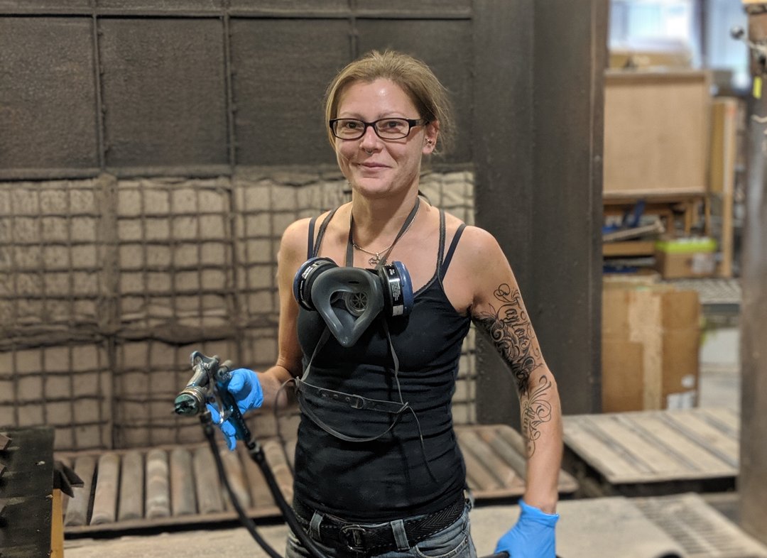 A woman wearing glasses and gloves in a factory.