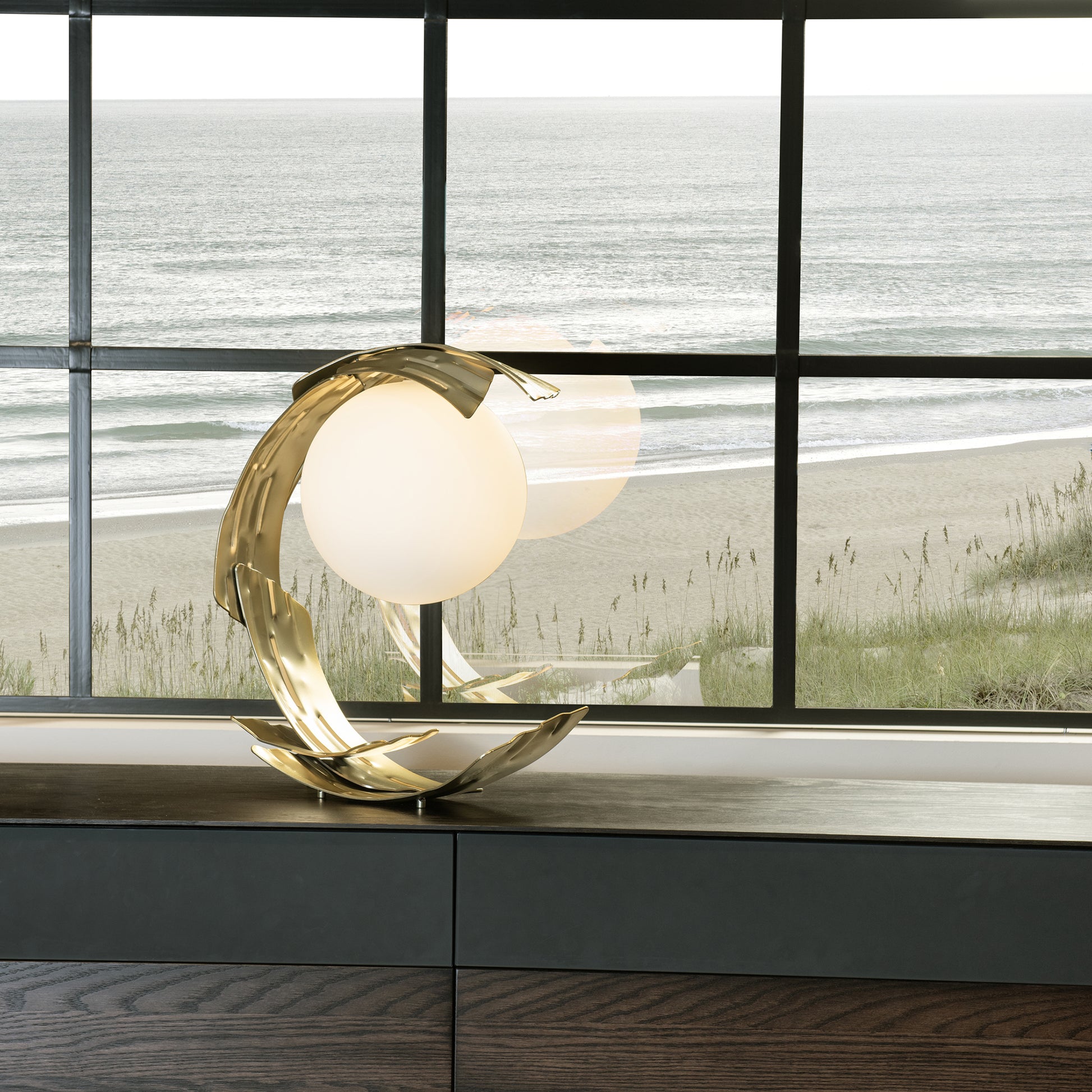 Modern Hubbardton Forge Crest Table Lamp with circular design on dark wooden table.