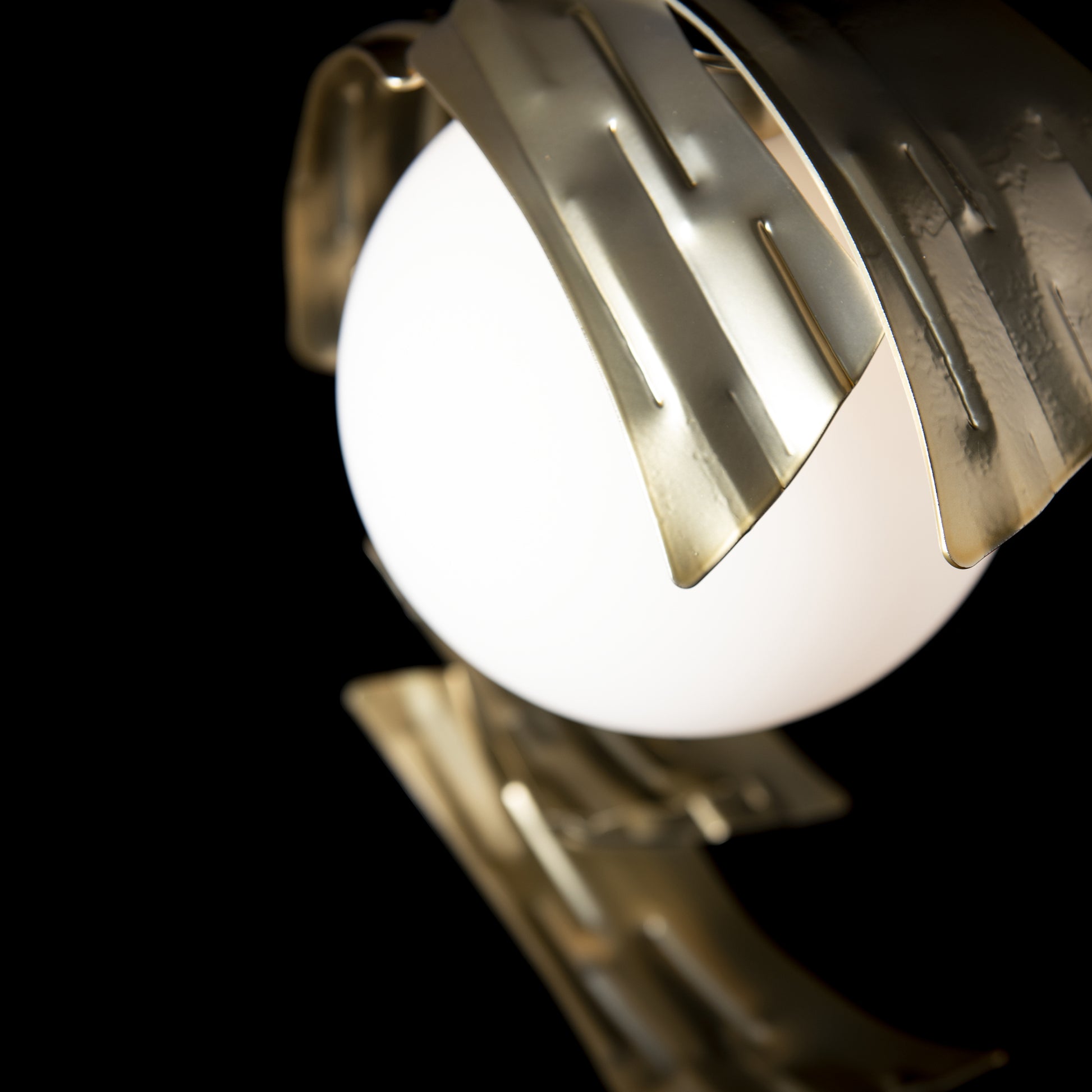 Crest Table Lamp with spherical white light and abstract hand-forged steel ribbons by Hubbardton Forge.