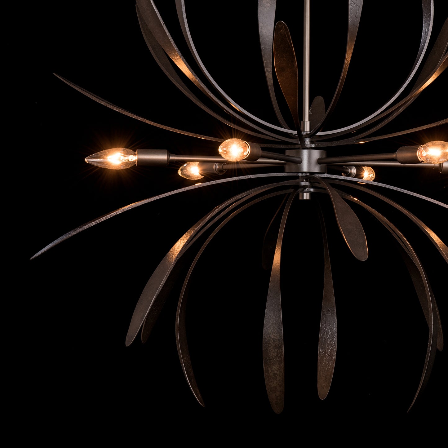 Dahlia Chandelier by Hubbardton Forge with leaf-like arms and glowing bulbs, crafted through eco-friendly metal forging.