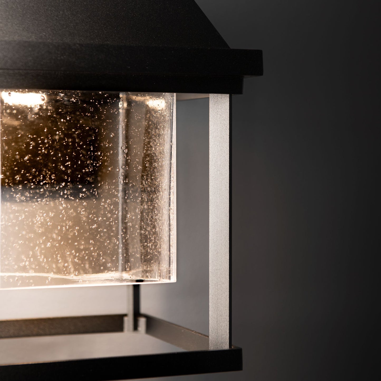 Hubbardton Forge Dorset Small Dark Sky Friendly Outdoor Sconce featuring a black metal frame and glass with water droplets, highlighting its handcrafted design.