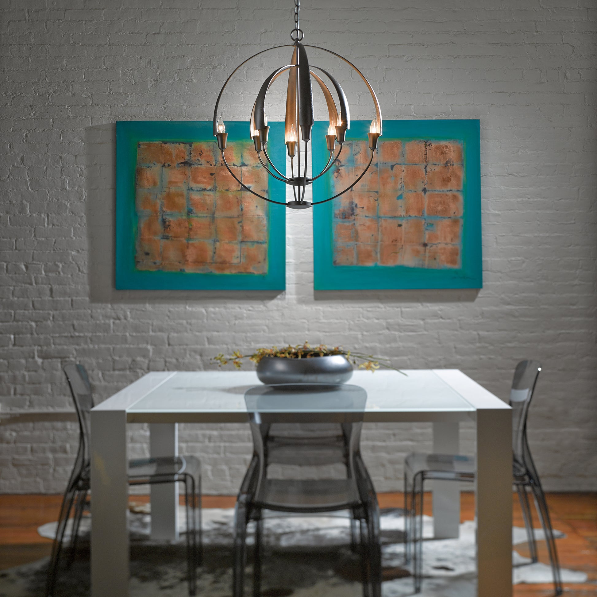 A Vermont dining room featuring a table and chairs illuminated by a stylish Hubbardton Forge Double Cirque Chandelier with candelabra bulbs.