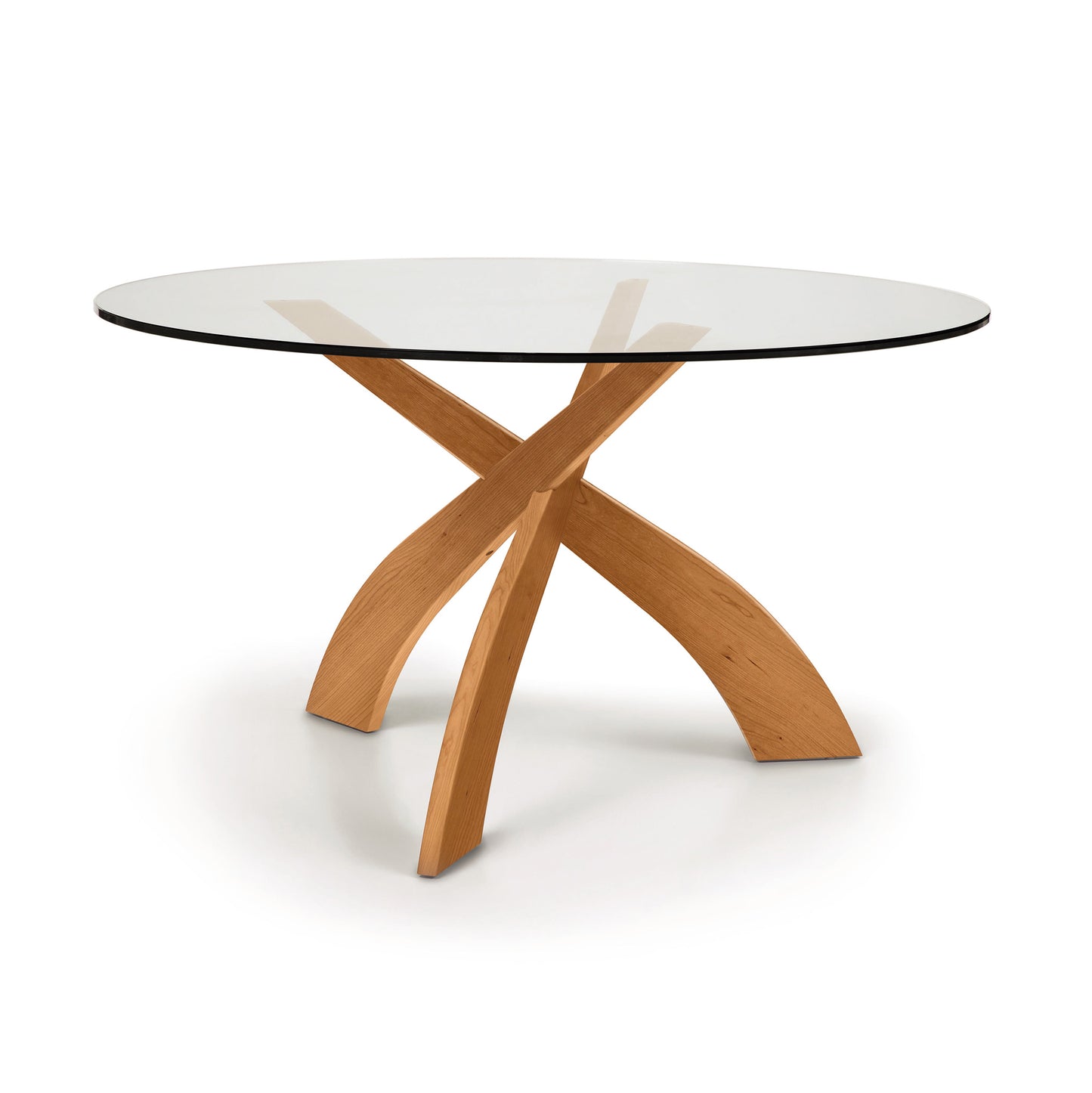 Copeland Furniture Entwine round dining table with a cherry wood sculpted base and clear glass top, modern design highlighted against a neutral background.