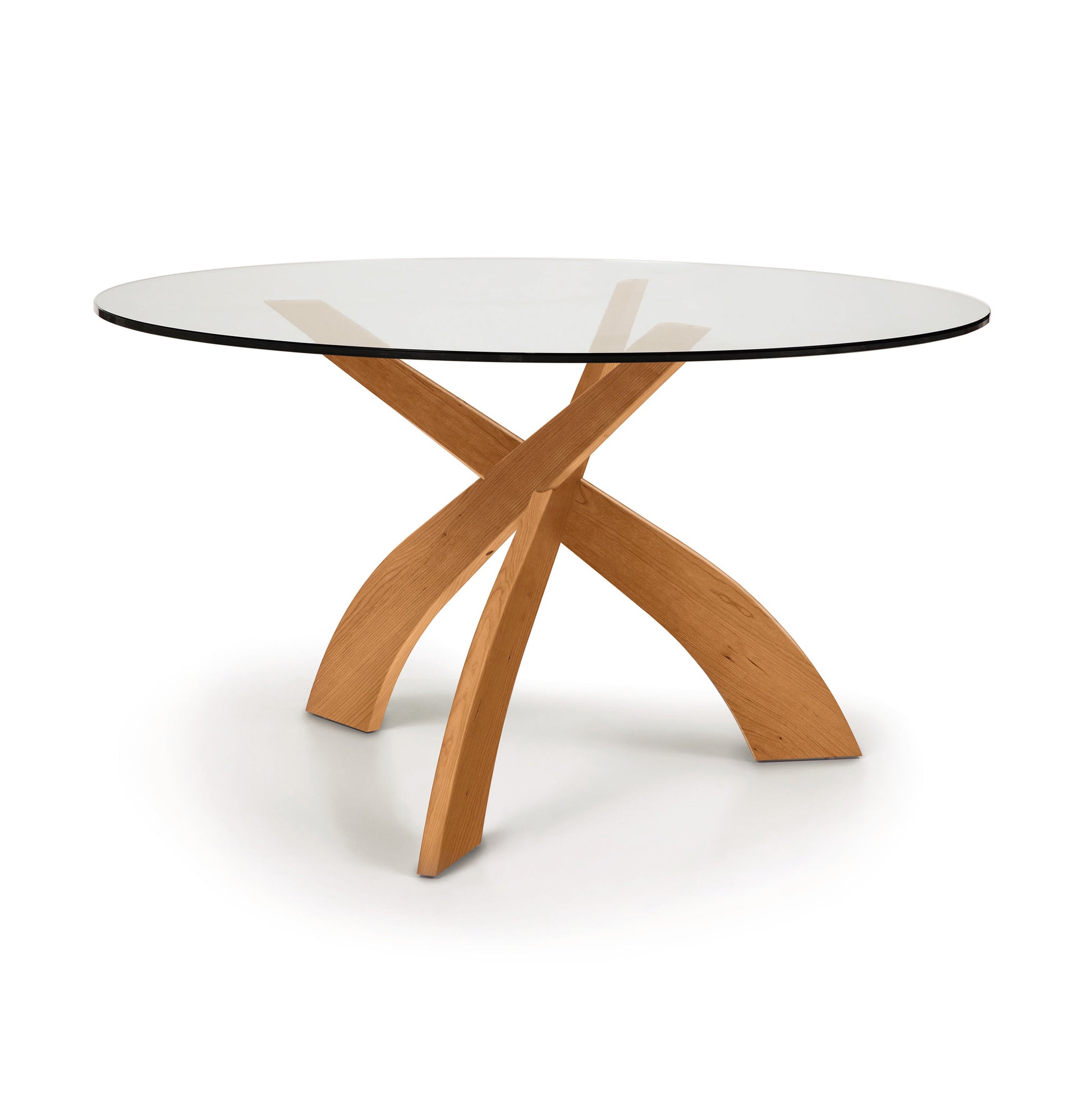 Copeland Furniture Entwine round dining table with a cherry wood sculpted base and clear glass top, modern design highlighted against a neutral background.