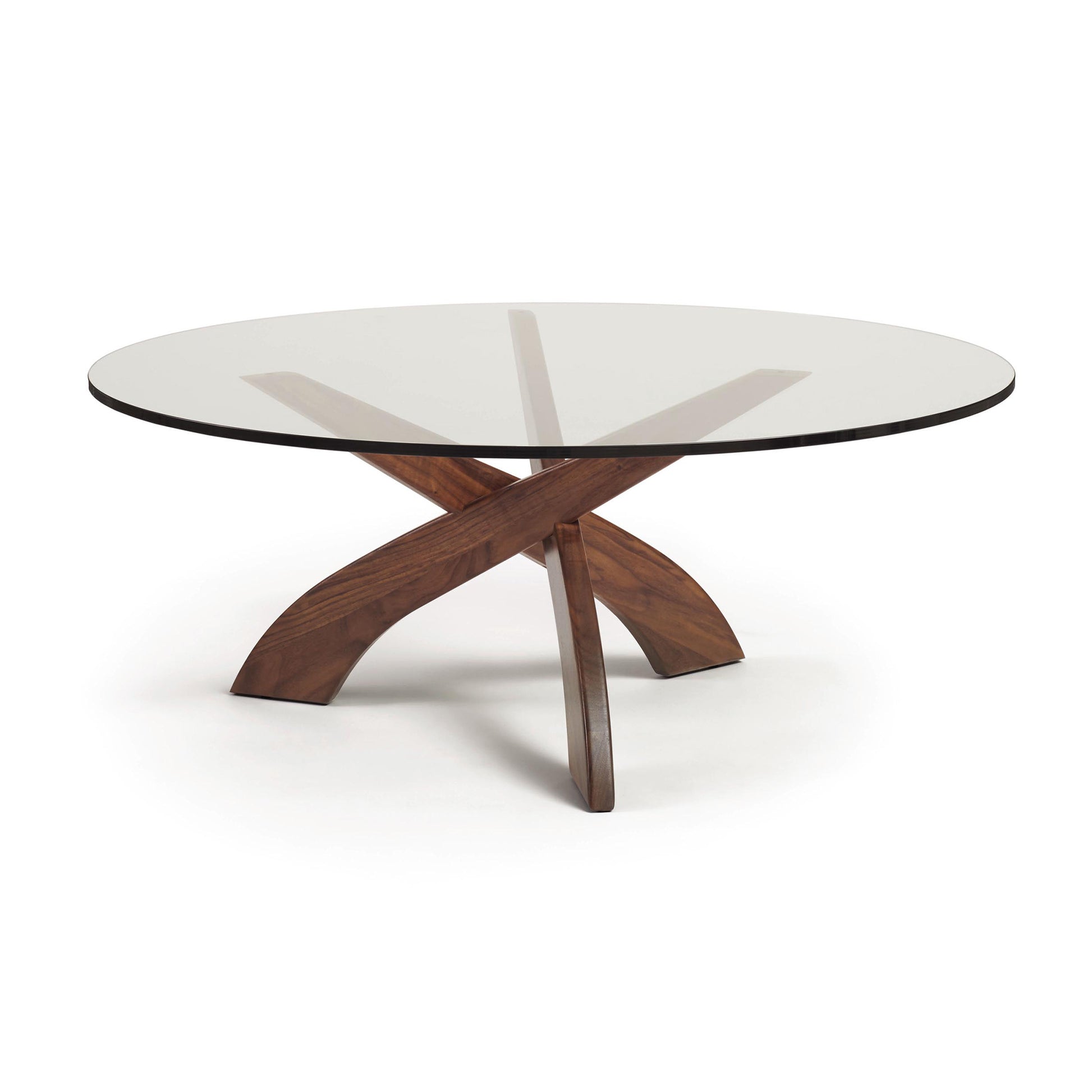 Entwine Round Coffee Table by Copeland Furniture with a thick glass top and sculptural walnut base of three curved legs.