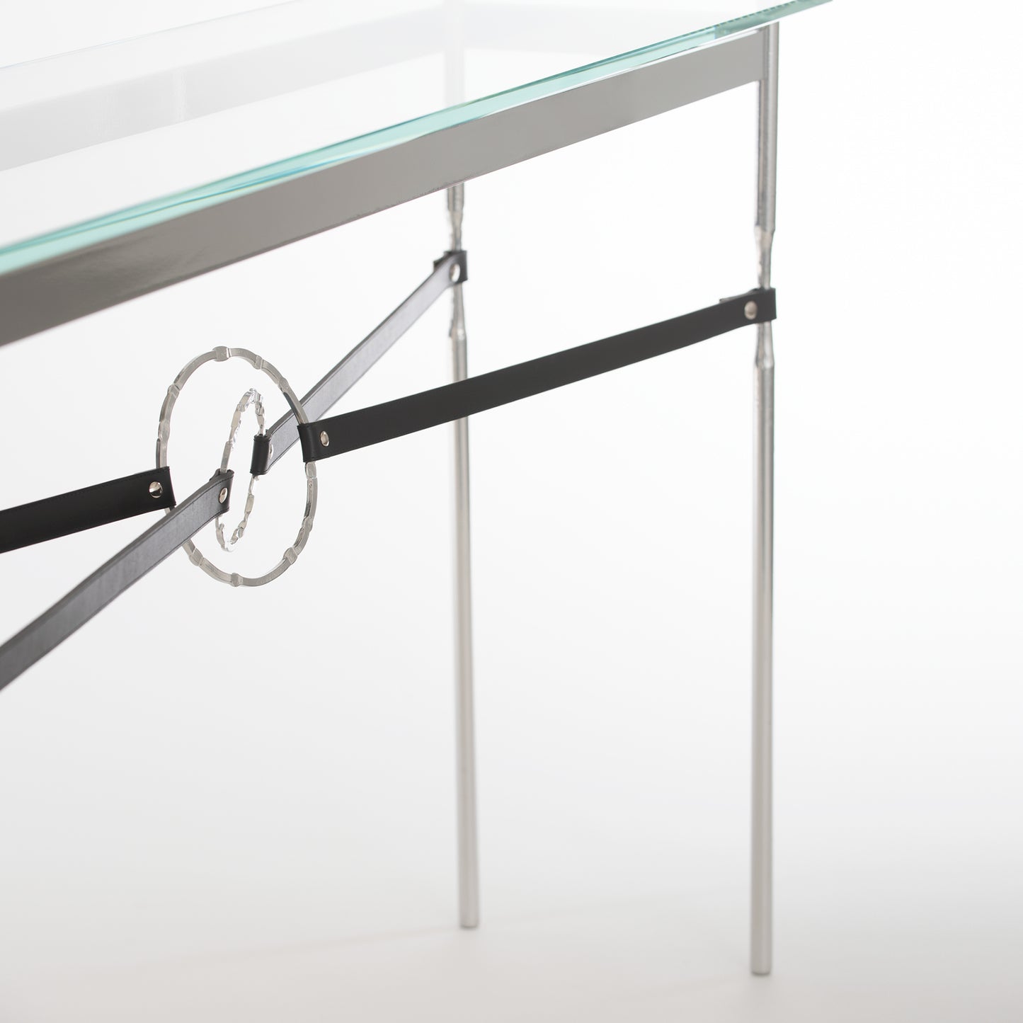 Equus Console Table by Hubbardton Forge with a glass top, sleek silver frame, and elegant circular accent on black bars.