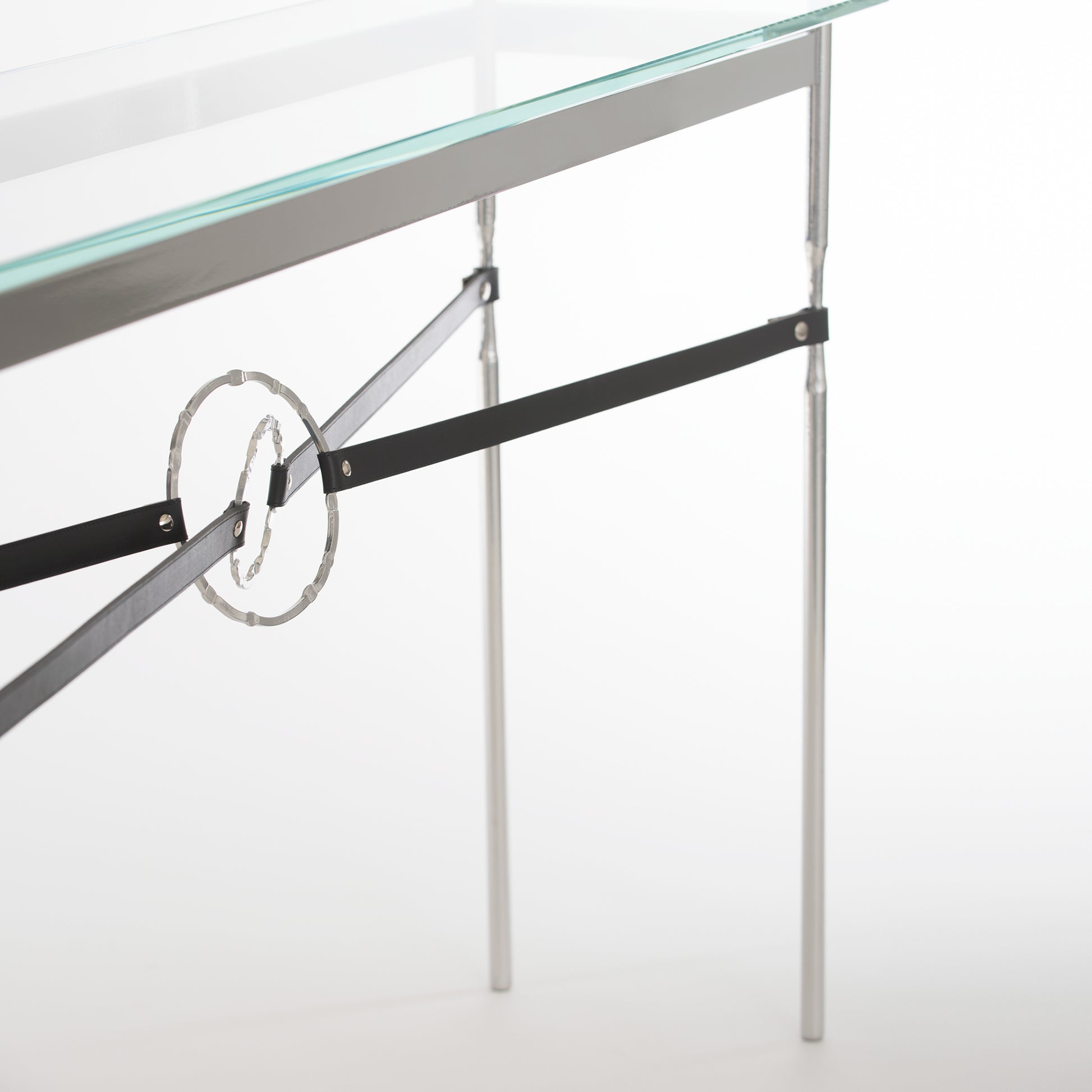 Equus Console Table by Hubbardton Forge with a glass top, sleek silver frame, and elegant circular accent on black bars.