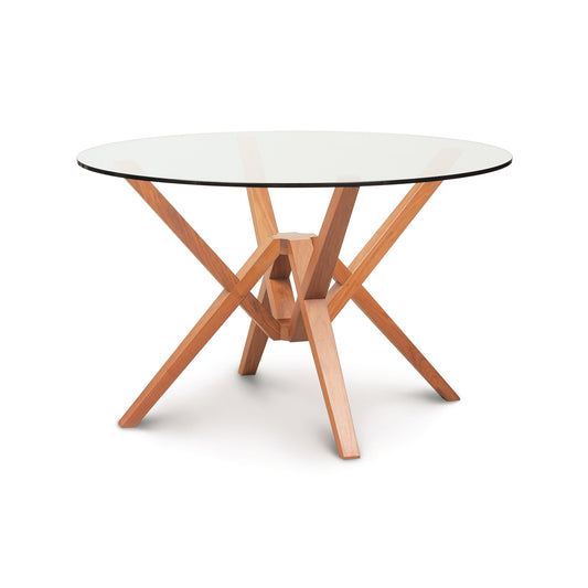 Copeland Exeter Round Glass Top Table with an intricate geometric hardwood base, highlighting modern craftsmanship and design.