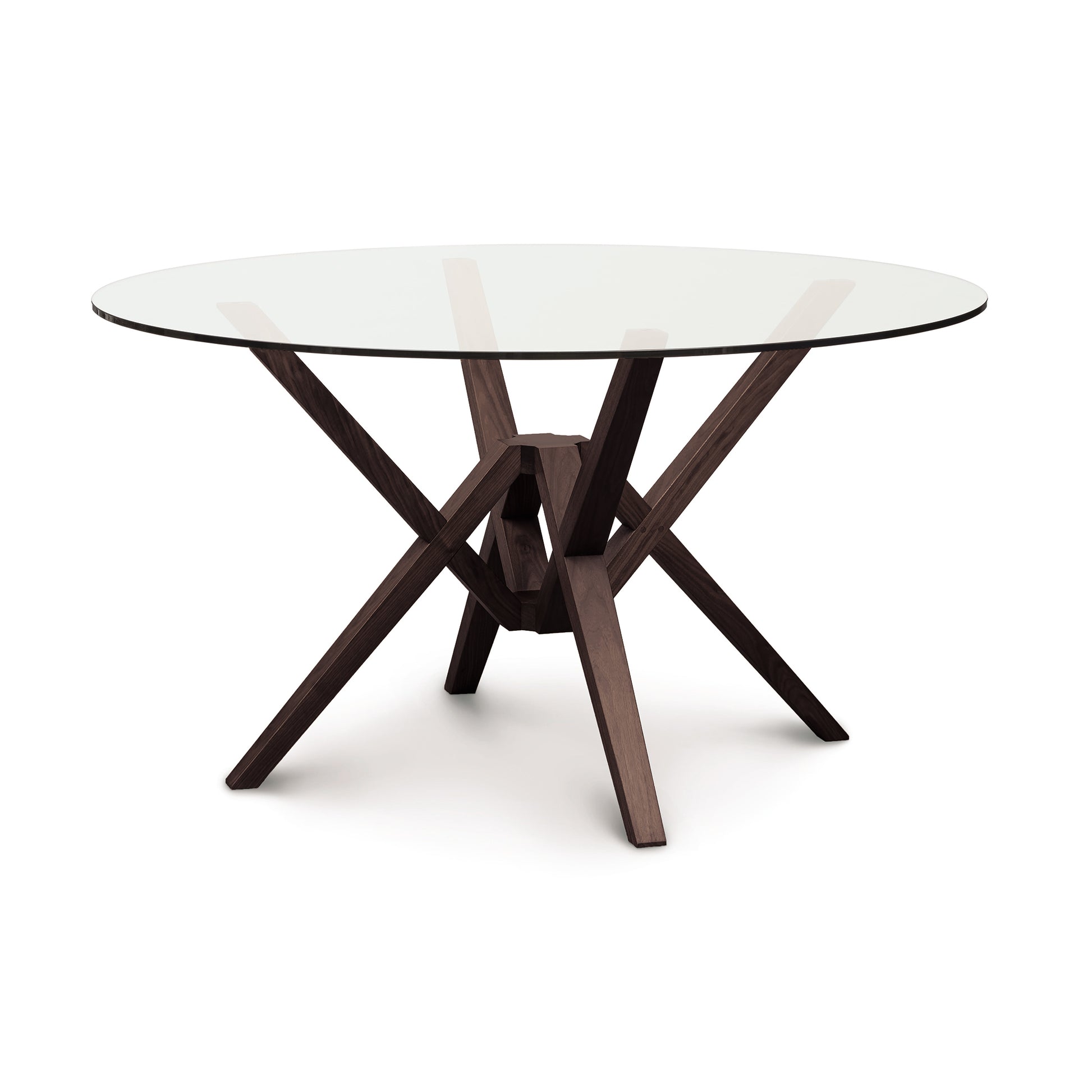 Exeter round glass top dining table by Copeland Furniture featuring a sculpted solid wood base, highlighting its modern craftsmanship.