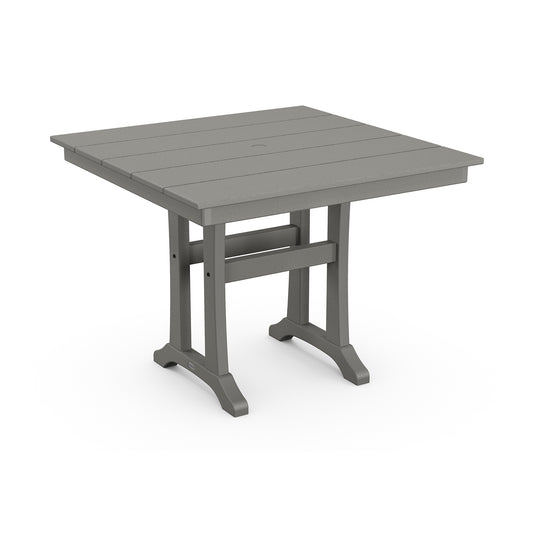 A modern, square outdoor table with a slatted top and sturdy legs, crafted from POLYWOOD lumber in a neutral gray color. The POLYWOOD Farmhouse Trestle 37" Dining Table has a centered hole likely for an umbrella.