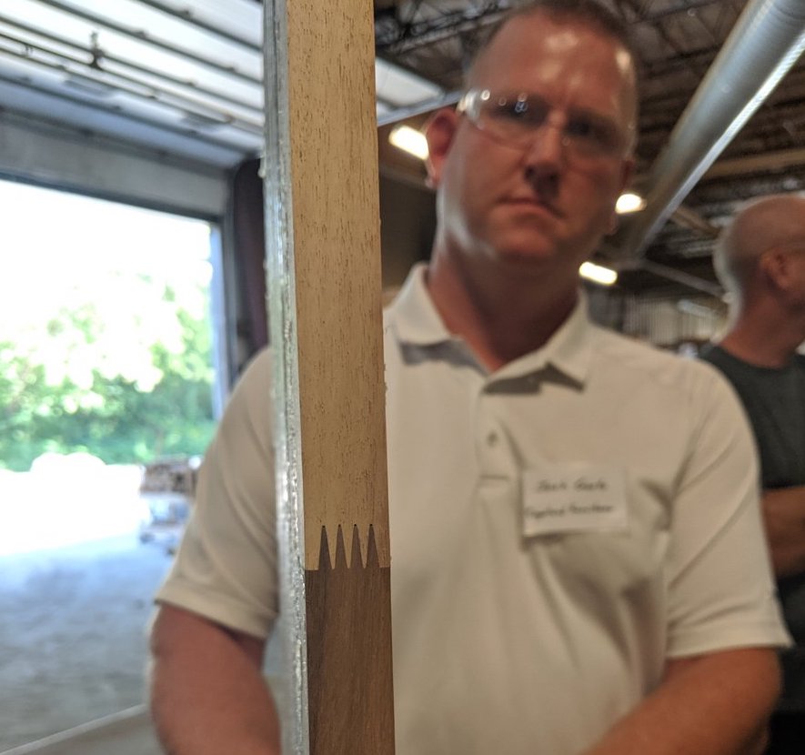 A man is holding a piece of wood in front of him.