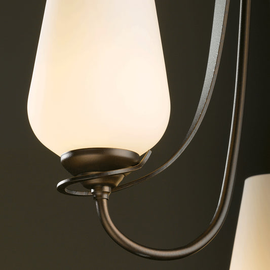 Elegant wall sconce featuring a white tapered shade and dark metal frame, inspired by Hubbardton Forge's Flora 3-Arm Chandelier design.